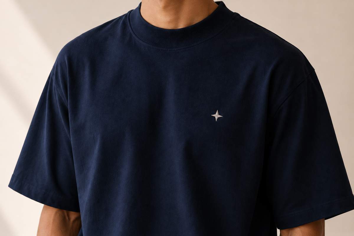 Close view of a navy TELLS crewneck shirt with short sleeves and a small embroidered motif