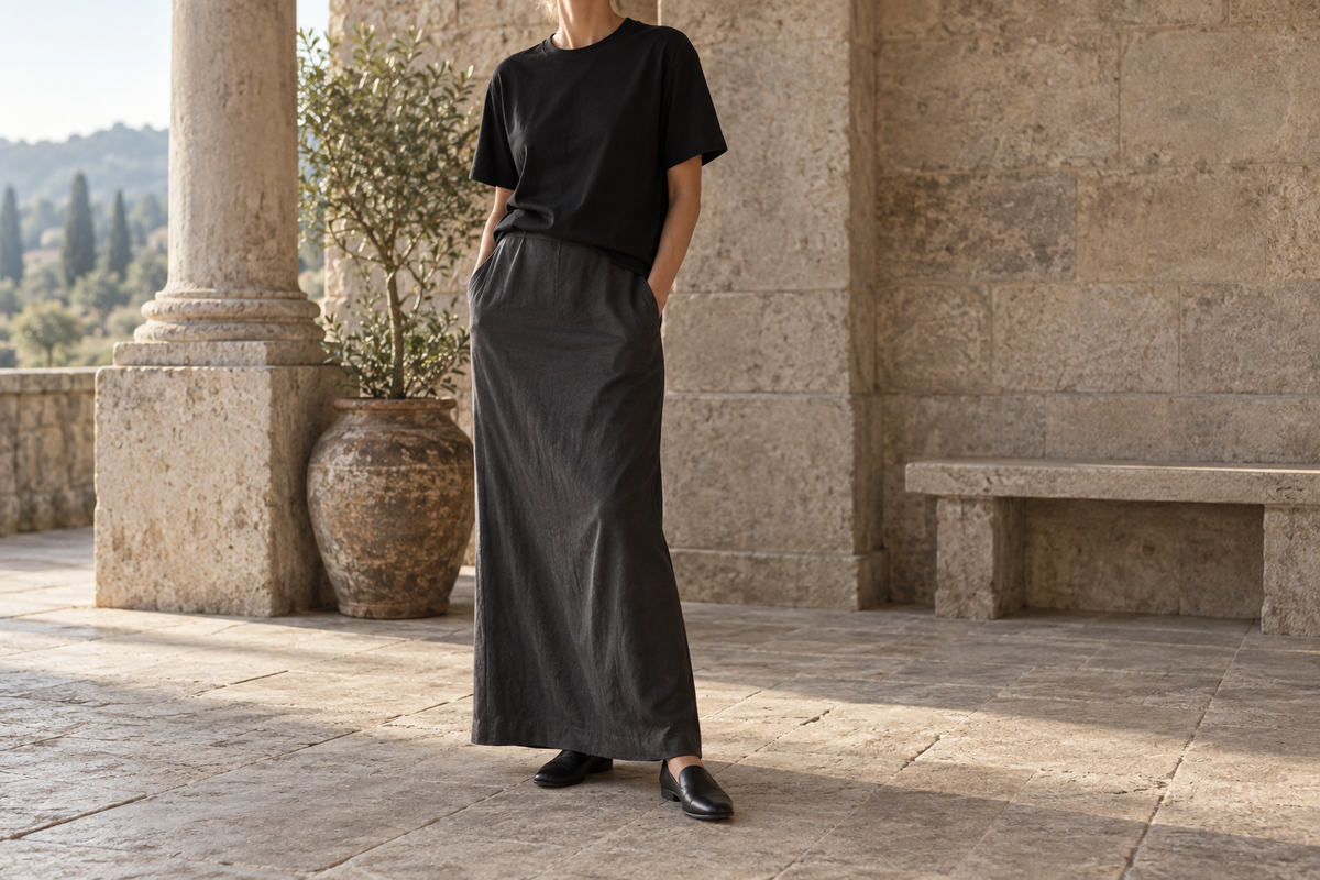 Black T shirt styled with a charcoal long skirt and dark flats in a stone courtyard