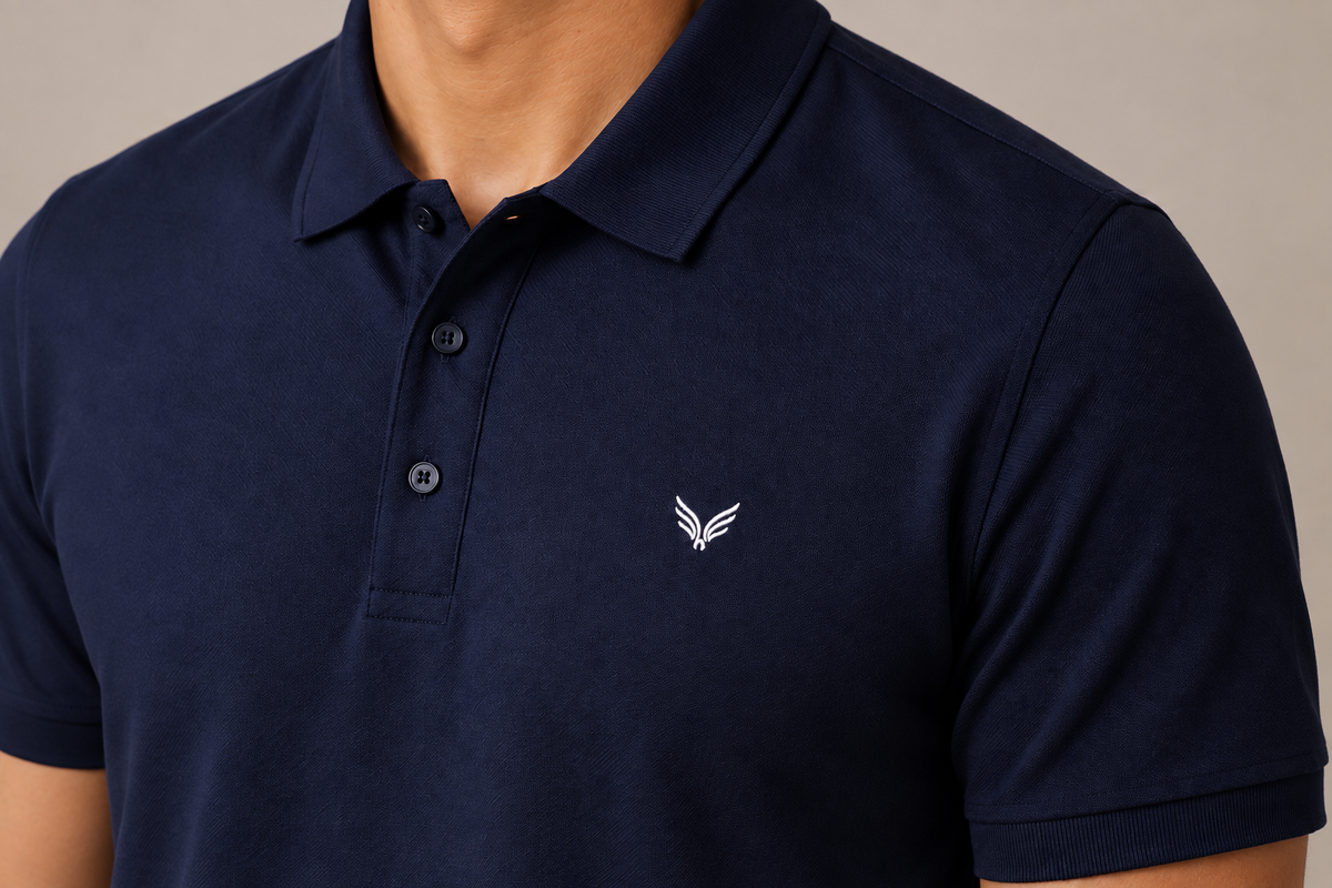 Close view of a navy TELLS polo collar, button placket, and embroidered chest mark