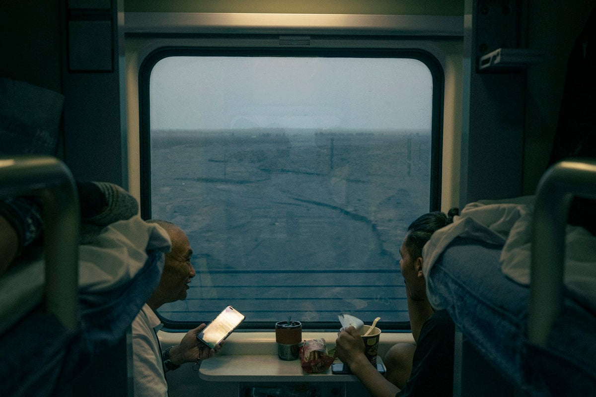 Travellers seated inside a train compartment at night