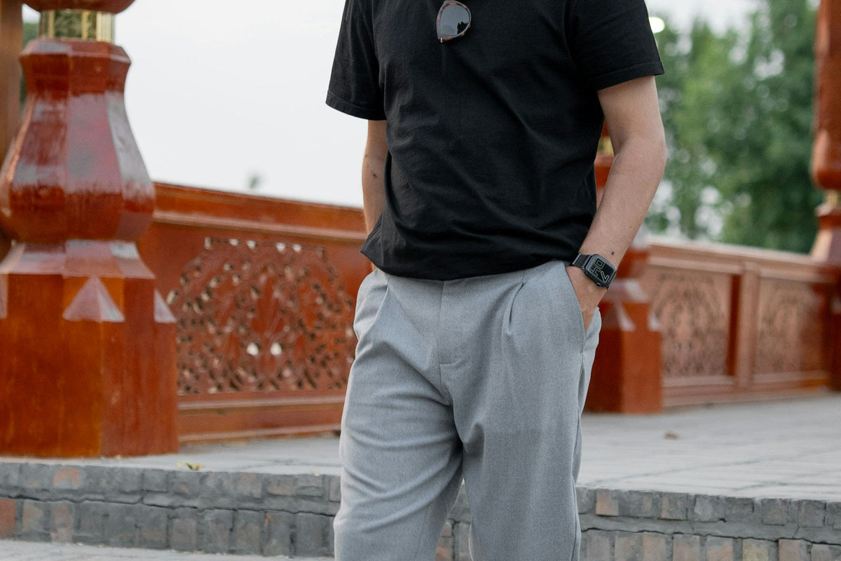 Man wearing slim grey trousers with a black shirt in a modern street-style outfit