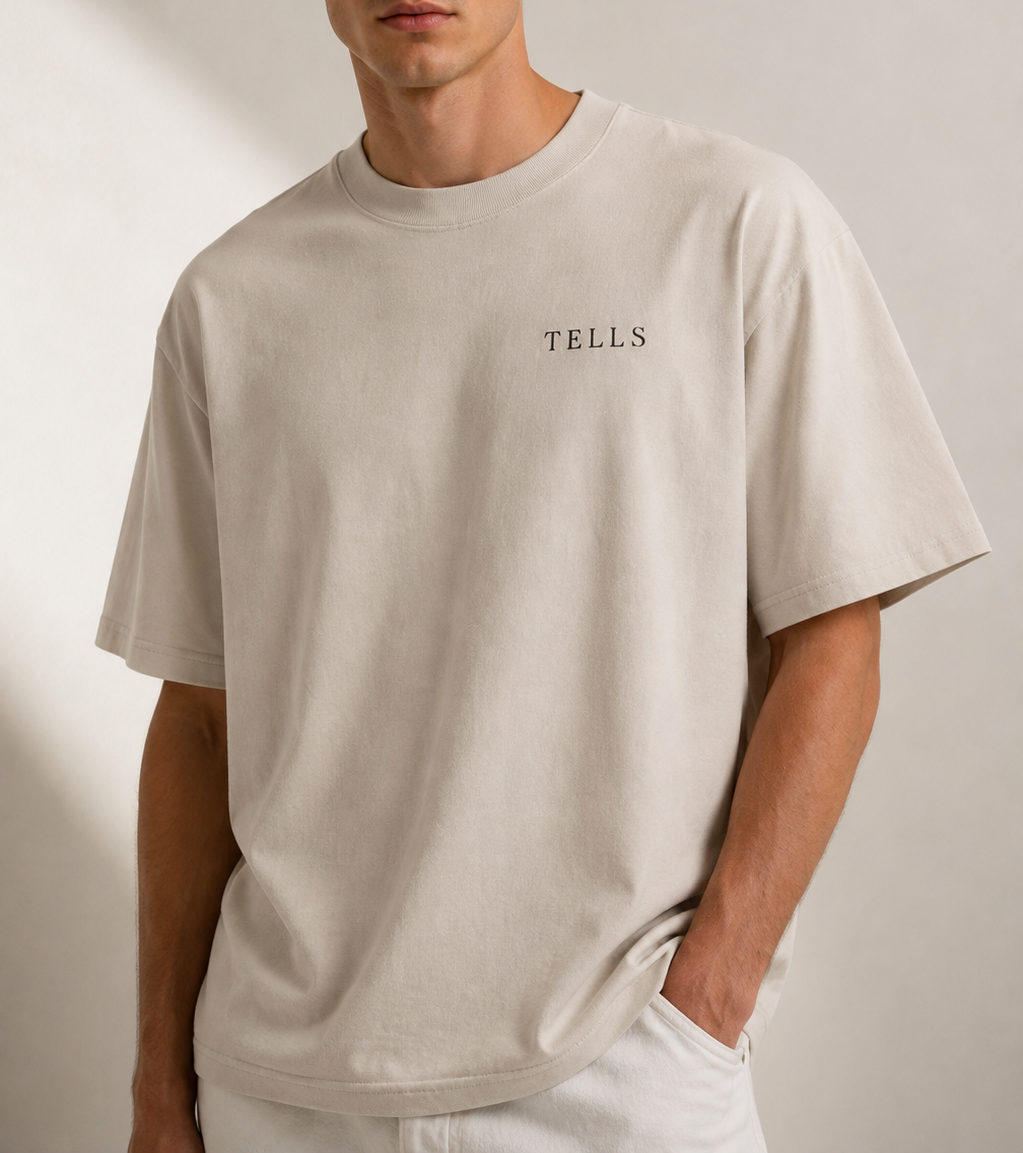 Man wearing a heavyweight cotton TELLS T shirt in a faded bone colour