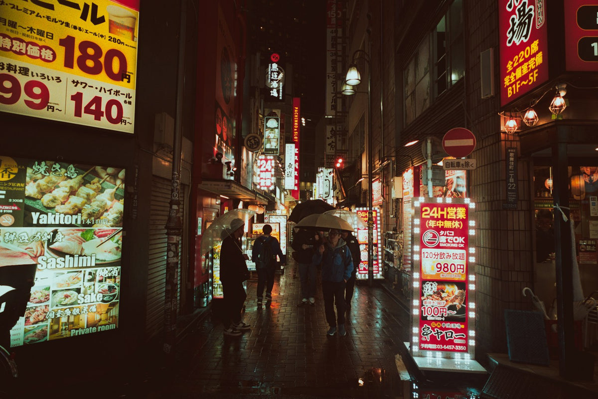 People walking through a rain-lit Tokyo street at night in autumn