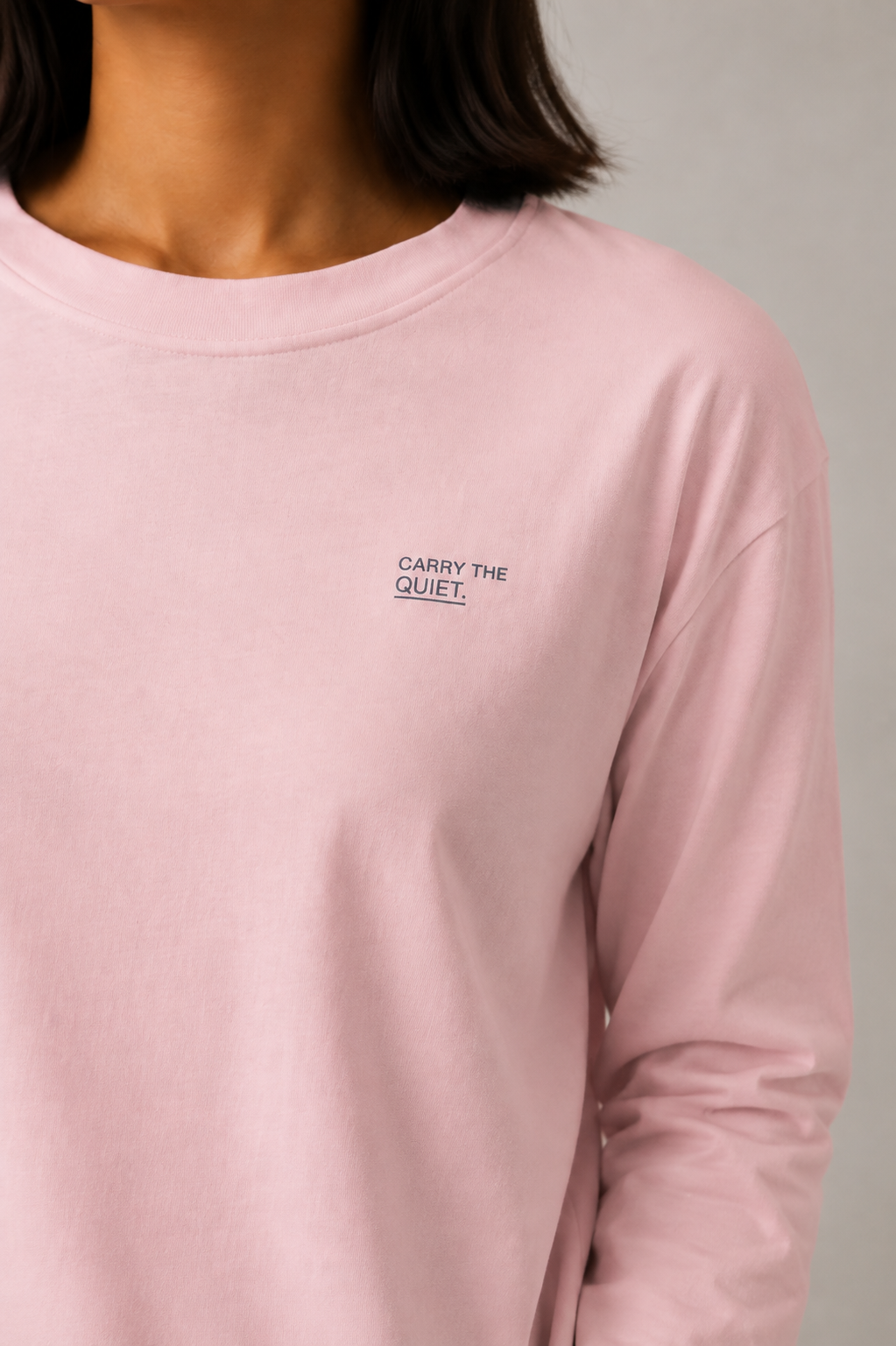 Close studio detail of the Deep Ink Carry the quiet. print on the left chest of the Pink TELLS Quiet Sunfade Long Sleeve.