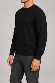 Three-quarter studio view of Still Hours Crewneck Sweater in Black, showing the plain silhouette and long sleeves.