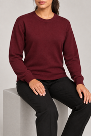Seated studio view of Quiet Form Crewneck Sweater in Burgundy, showing the natural knit drape.