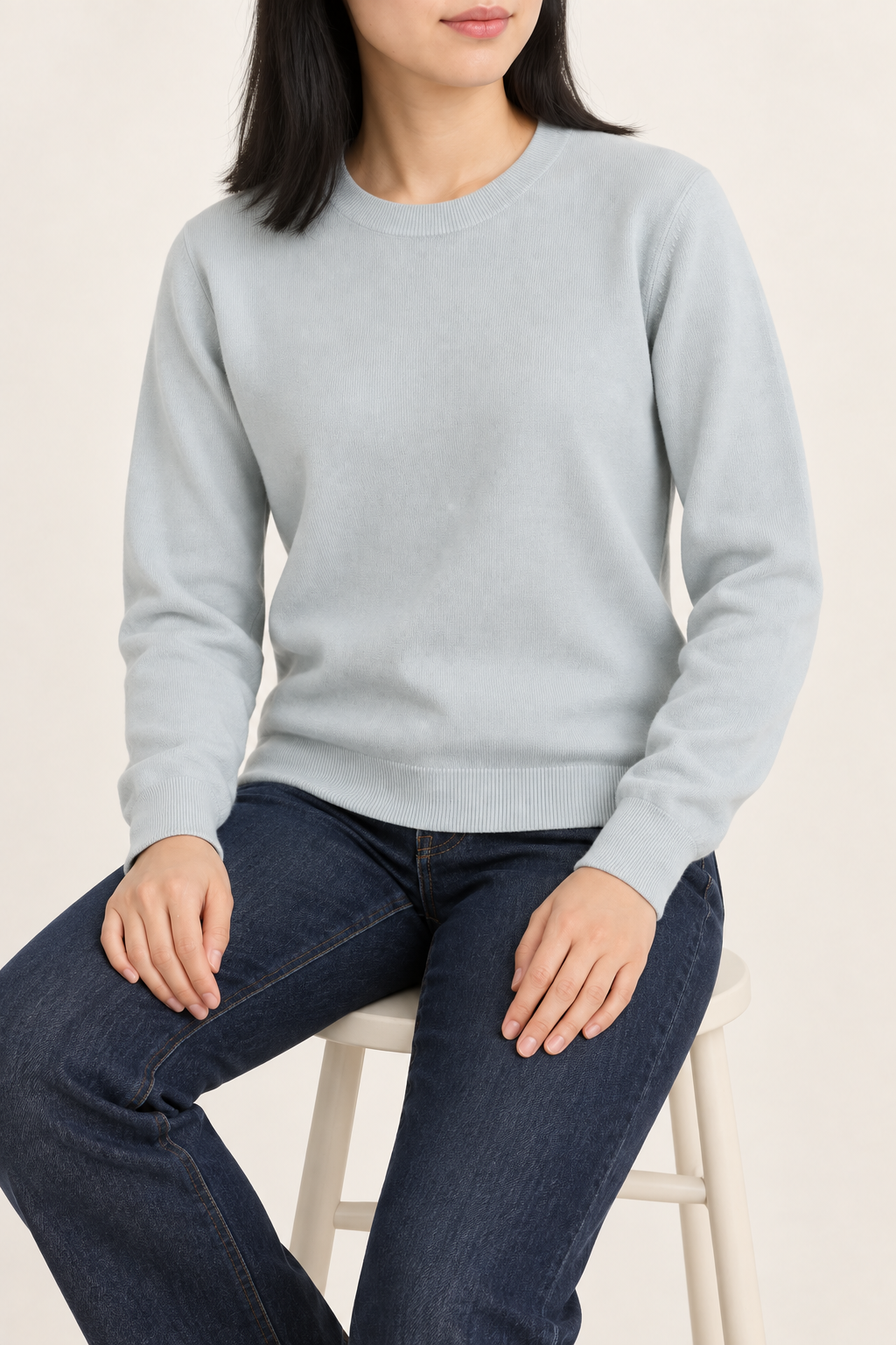 Seated studio view of Quiet Form Crewneck Sweater in Powder, showing the natural knit drape.