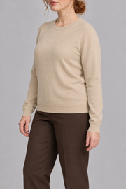 Three-quarter studio view of Quiet Form Crewneck Sweater in Beige, showing the long sleeves and classic silhouette.