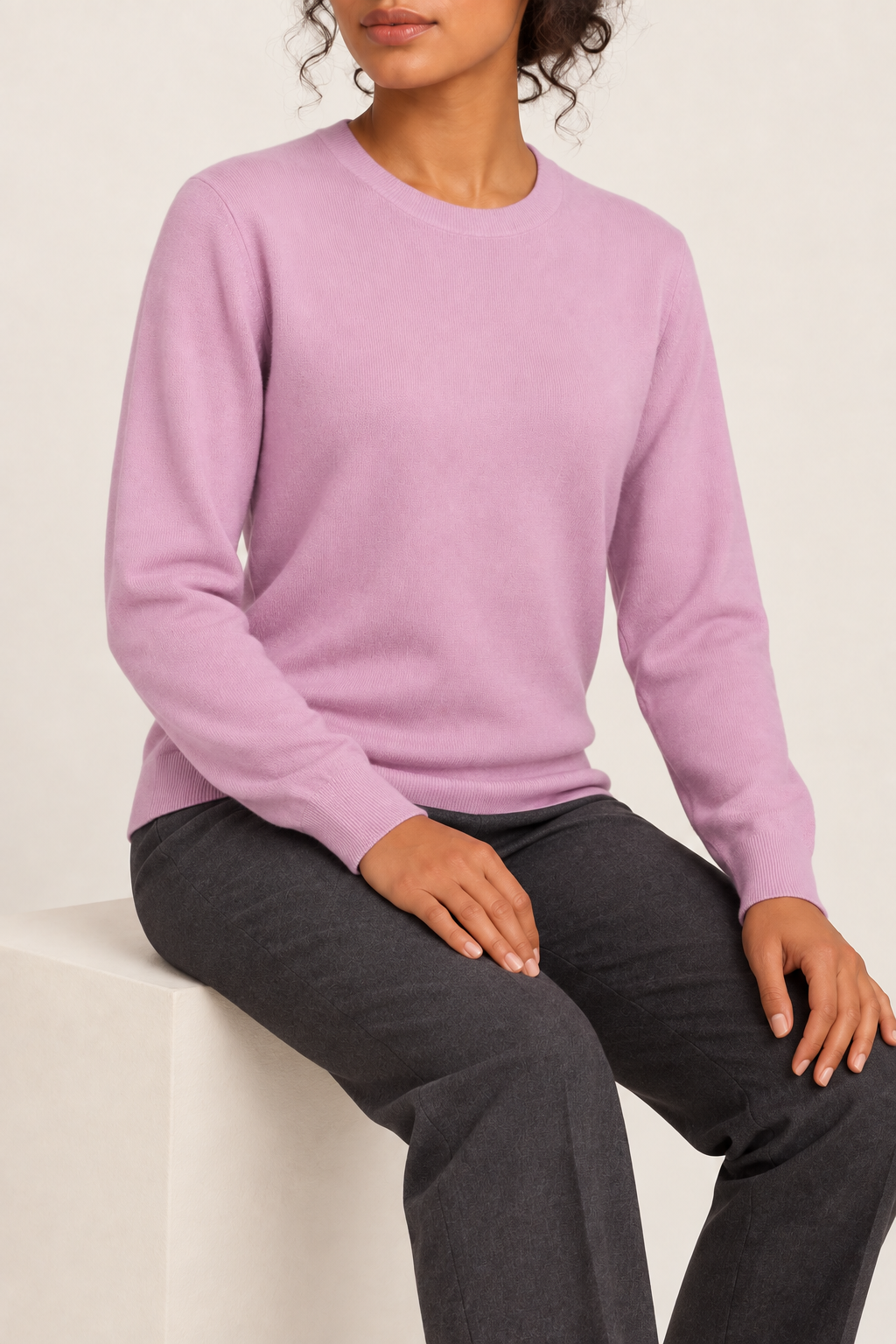 Seated studio view of Quiet Form Crewneck Sweater in Lilac, showing the natural knit drape.