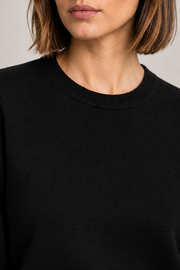 Close-up neckline detail of Quiet Form Crewneck Sweater in Black, showing the fine knit and ribbed collar.
