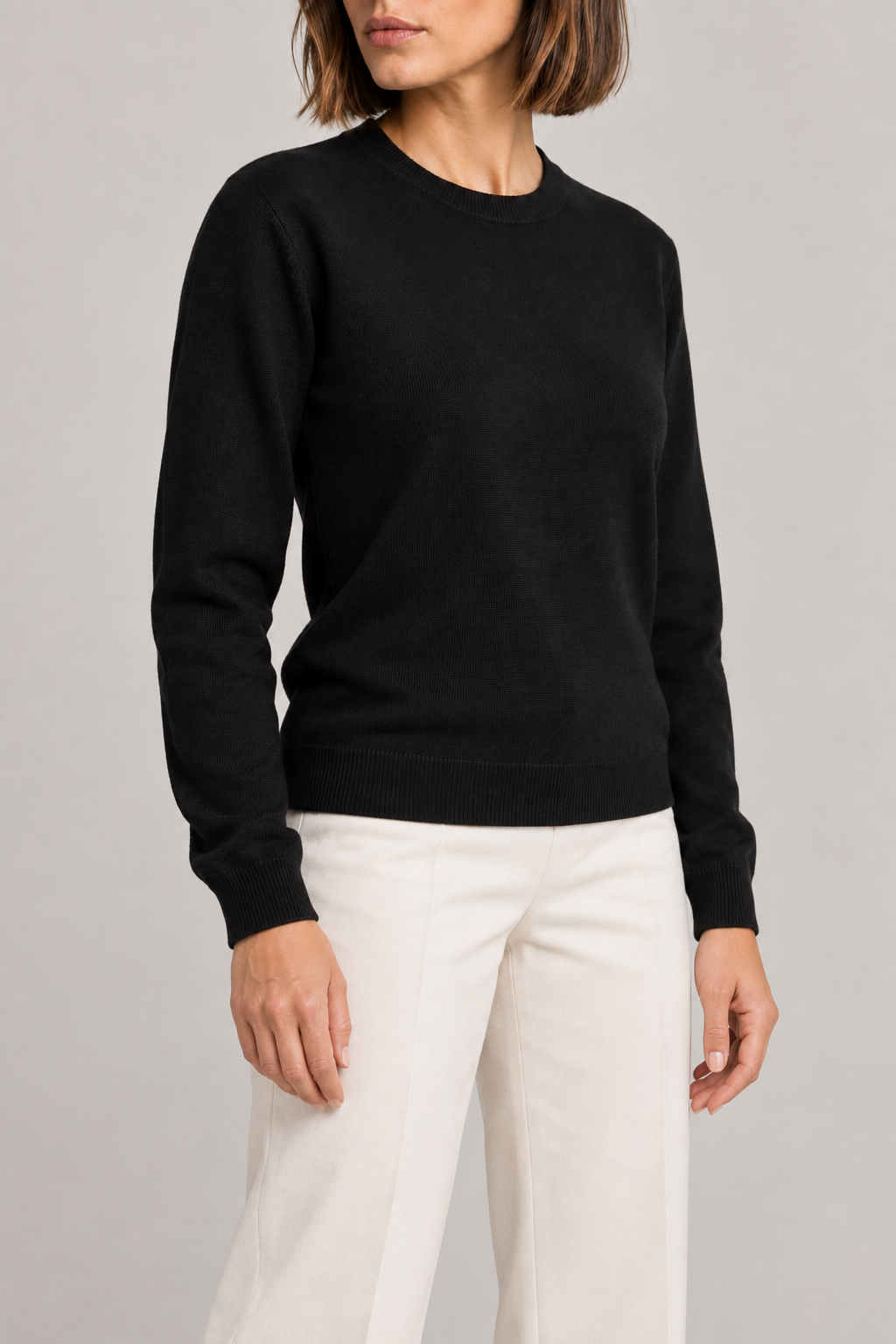 Three-quarter studio view of Quiet Form Crewneck Sweater in Black, showing the long sleeves and classic silhouette.