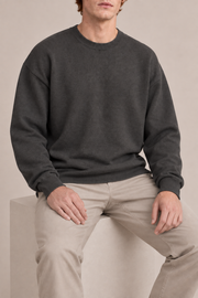 Slow Days Relaxed Crewneck in Charcoal. Seated view showing the charcoal sweater natural drape.