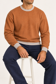 Slow Days Relaxed Crewneck in Rust with Coco Trim. Seated view showing the relaxed Rust knit drape and Coco trim.