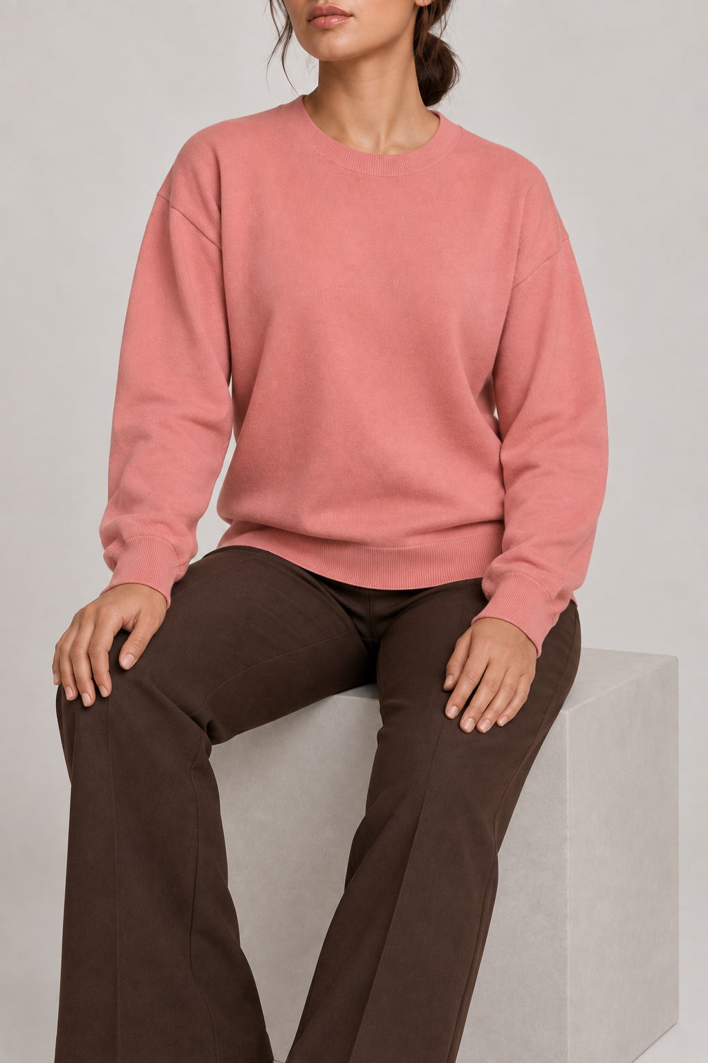Soft Pause Relaxed Crewneck in Coral. Seated view showing the relaxed Coral knit drape.