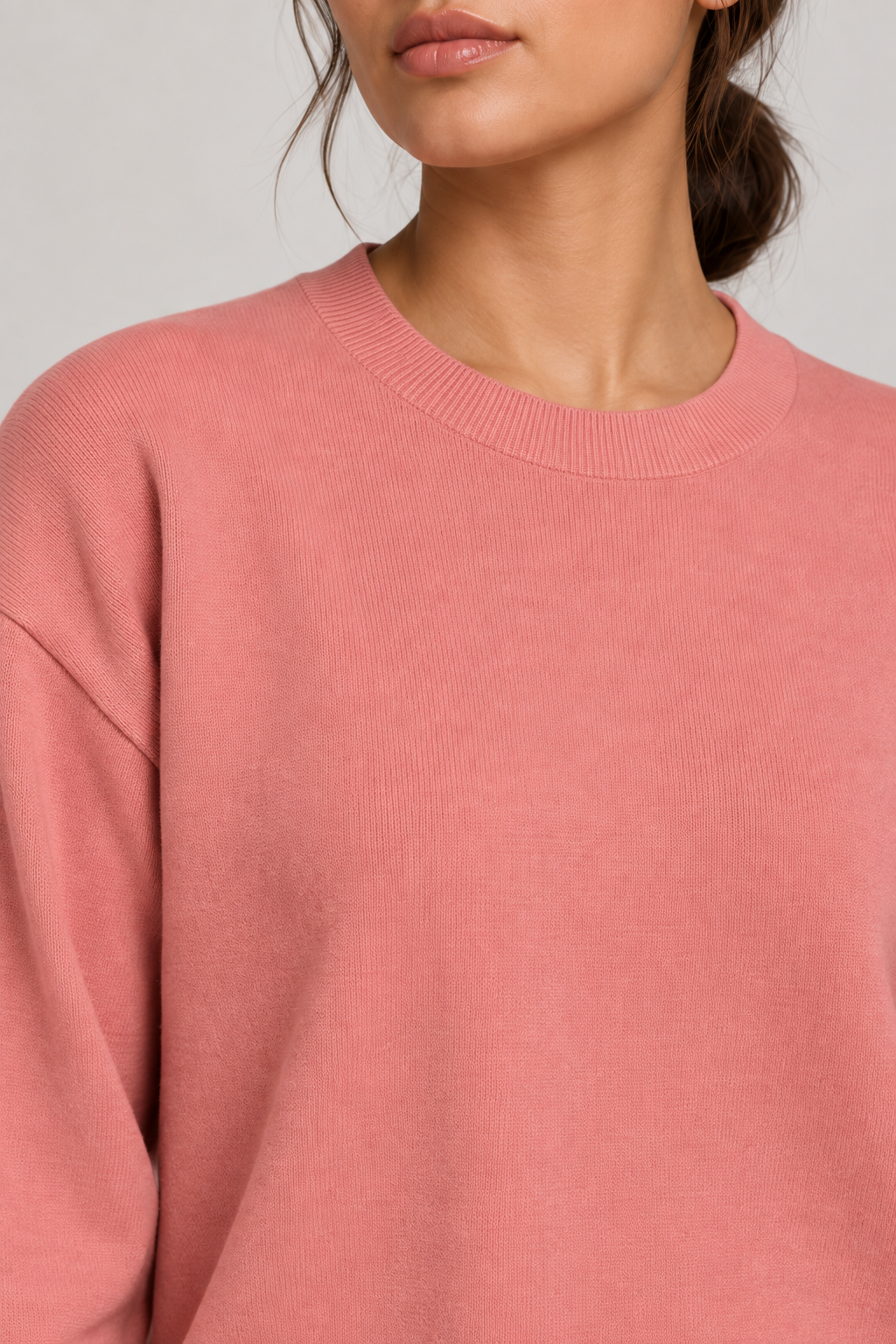 Soft Pause Relaxed Crewneck in Coral. Close-up showing the fine Coral knit and ribbed crew neckline.