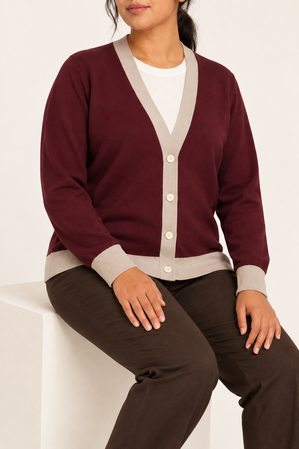 Soft Interval Cardigan in Burgundy with Coco Trim. Seated studio view showing the long sleeves and natural knit drape.