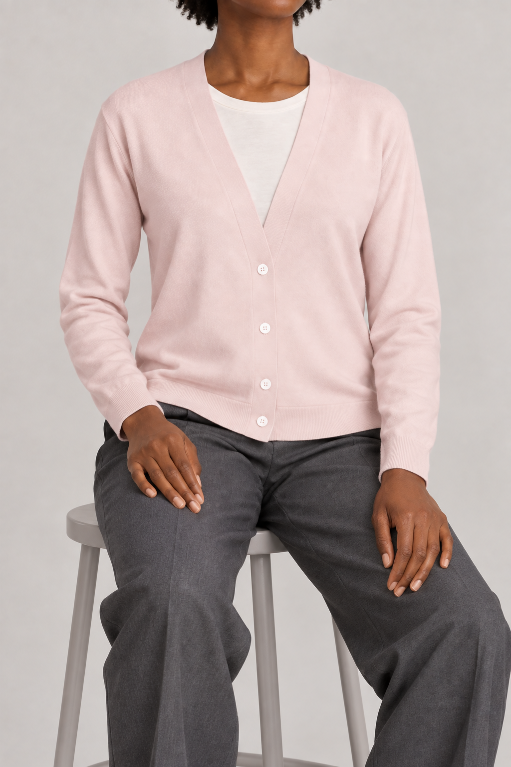 Soft Interval Cardigan in Lt Pink. Seated studio view showing the long sleeves and natural knit drape.
