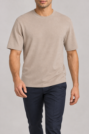 Walking studio view of Open Hours Knit T-Shirt in Coco, showing soft knit drape above navy trousers.
