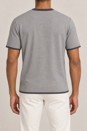 Rear studio view of Open Hours Knit T-Shirt in Grey with Charcoal Trim, showing plain grey back with dark hem and sleeve edges.