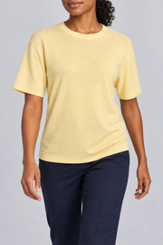 Walking studio view of Soft Tempo Knit T-Shirt in Mellow, showing yellow knit drape above navy trousers.
