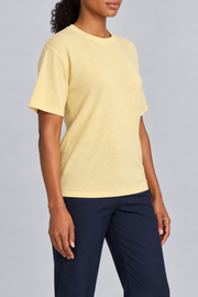Three-quarter studio view of Soft Tempo Knit T-Shirt in Mellow, showing short sleeves and clean yellow silhouette.