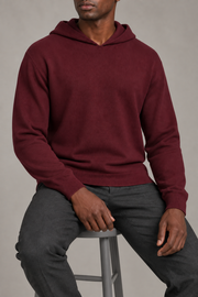 Seated view showing the soft knit drape and long sleeves of Off Hours Knit Hoodie in Burgundy.