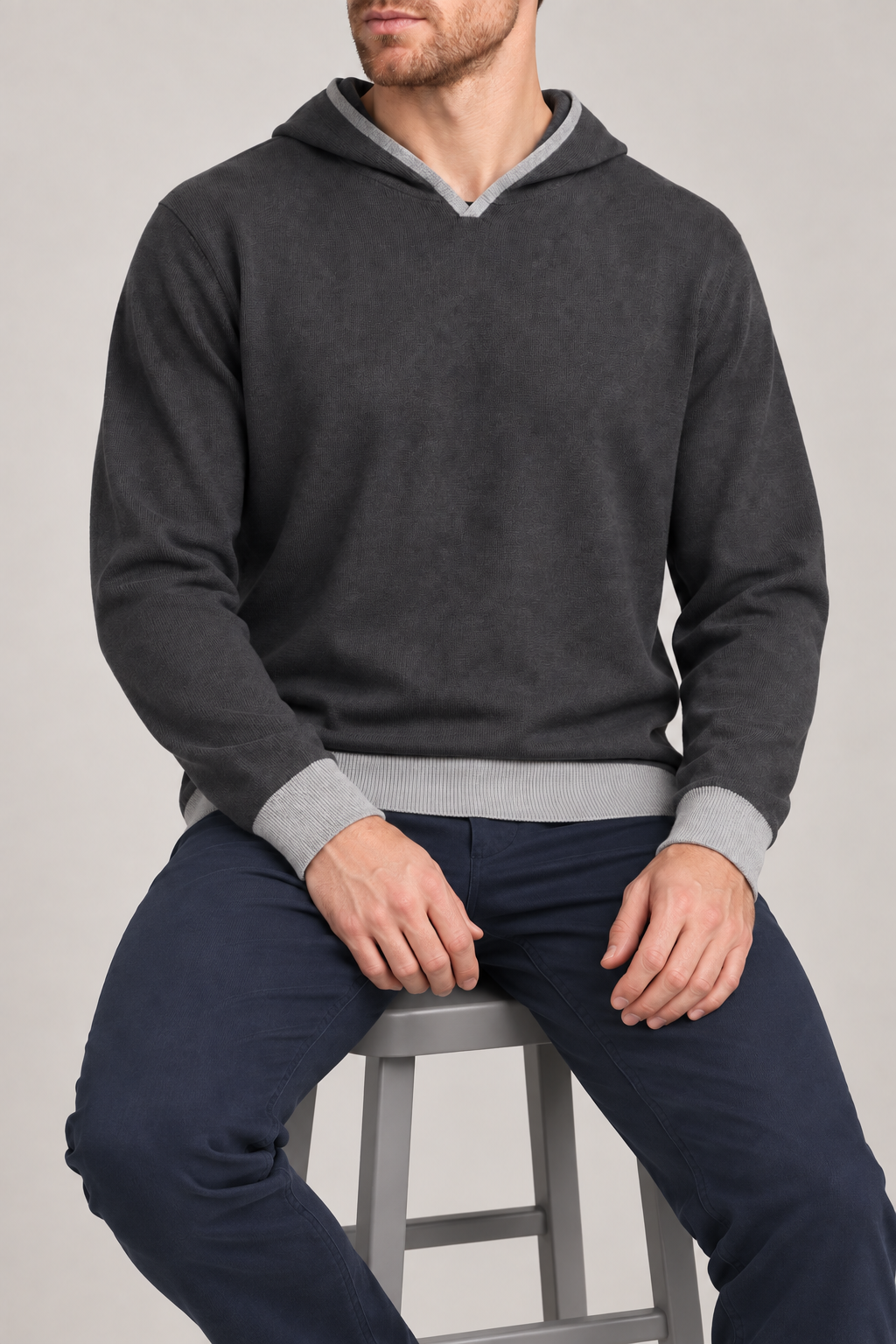 Seated view showing the relaxed knit drape and lighter edges of Off Hours Knit Hoodie in Charcoal with Grey Trim.