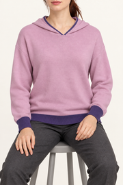 Seated view showing the soft knit drape and purple edges of Quiet Ease Knit Hoodie in Lilac with Violet Trim.