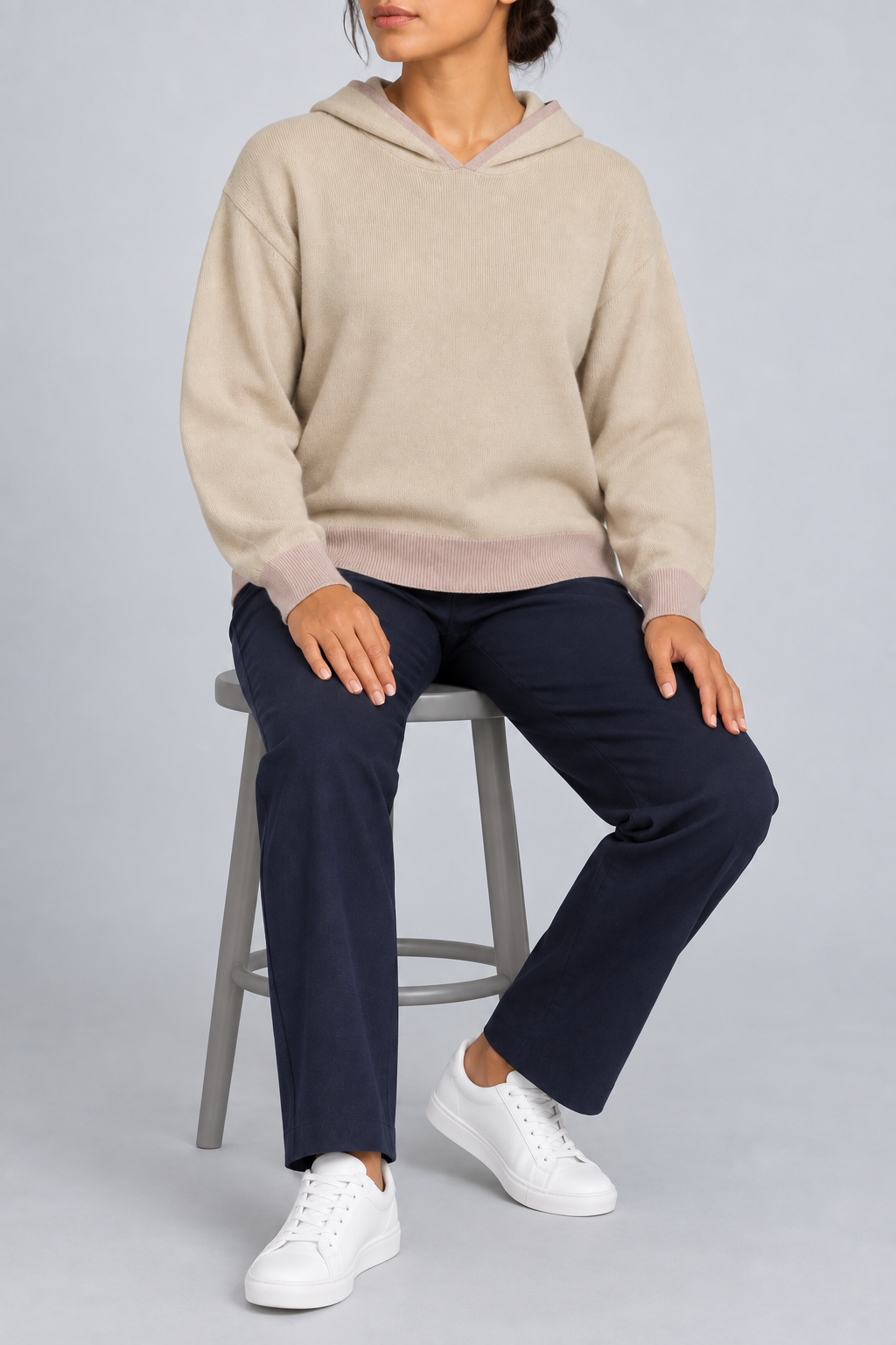 Seated view showing the soft knit drape and tonal edges of Quiet Ease Knit Hoodie in Beige with Taupe Trim.