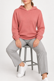 Seated view showing the soft knit drape and long sleeves of Quiet Ease Knit Hoodie in Coral.
