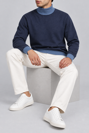 Seated view showing the Navy knit drape and contrasting Denim cuffs of Still Season Turtleneck in Navy with Denim Trim.