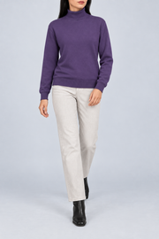 Walking view showing the Violet knit drape and long sleeves of Soft Horizon Turtleneck Sweater in Violet.