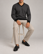 Seated view showing the Charcoal knit drape and Black cuffs of Quiet Angle V-Neck in Charcoal with Black Trim.