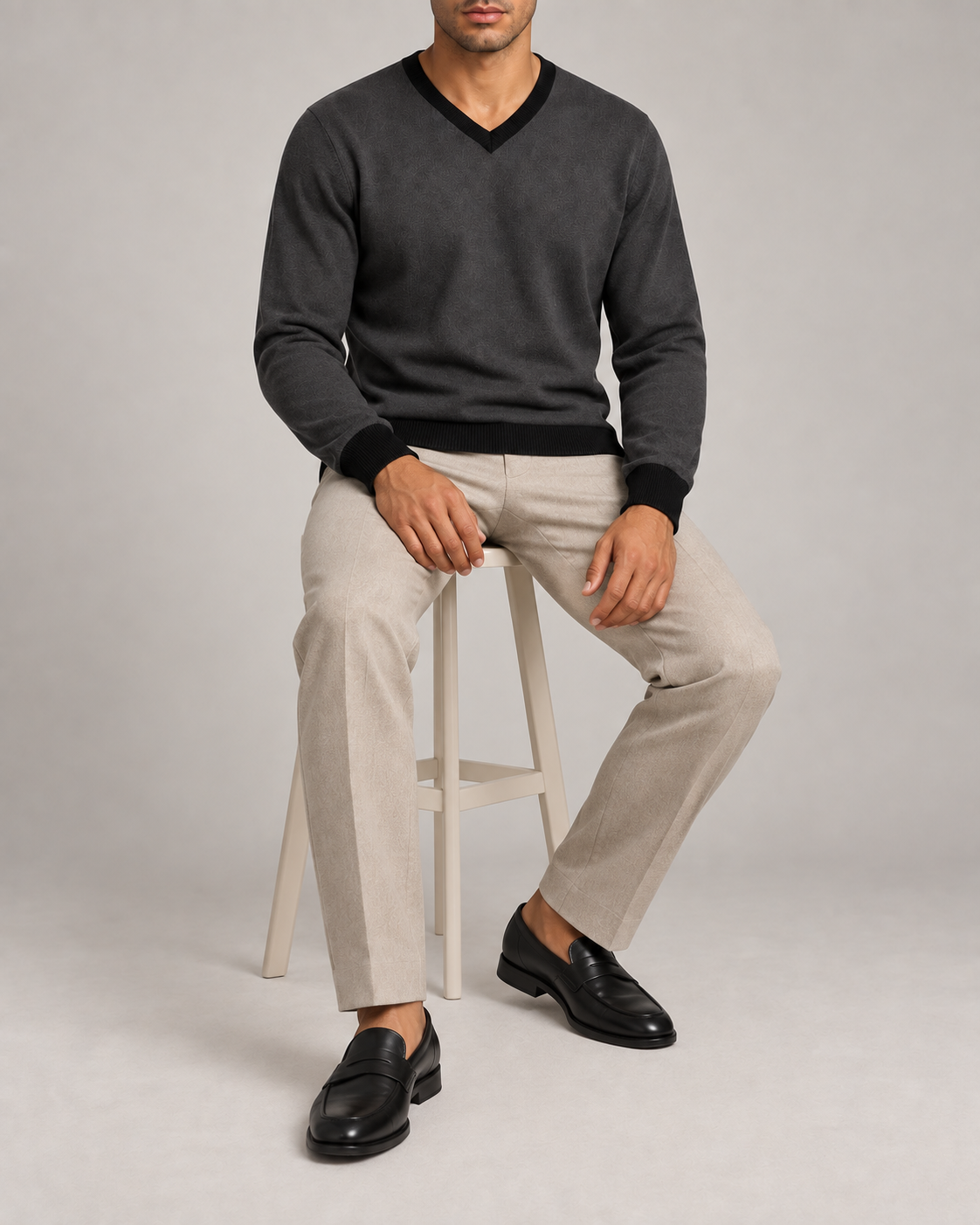 Seated view showing the Charcoal knit drape and Black cuffs of Quiet Angle V-Neck in Charcoal with Black Trim.