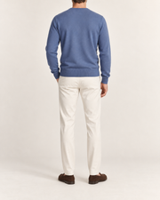Rear view showing the plain Denim blue back and tonal ribbed hem of Quiet Angle V-Neck Sweater in Denim.