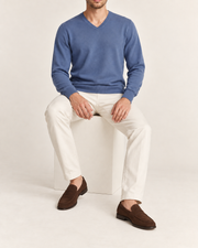Seated view showing the Denim blue knit drape of Quiet Angle V-Neck Sweater in Denim.