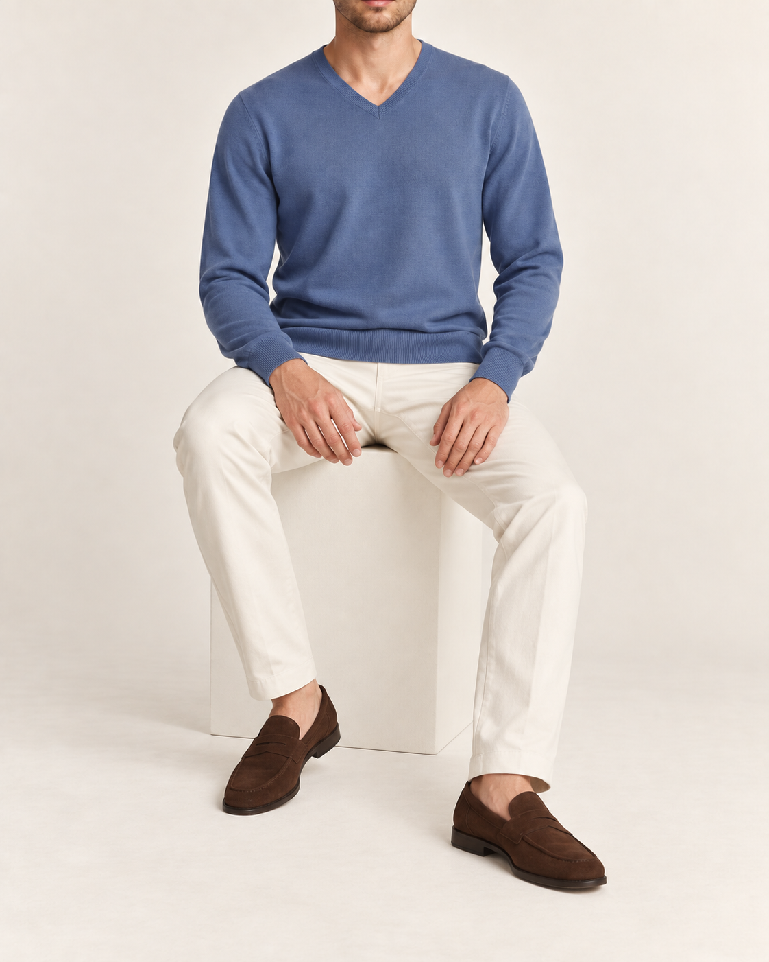 Seated view showing the Denim blue knit drape of Quiet Angle V-Neck Sweater in Denim.