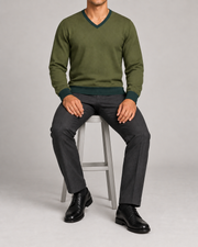 Seated view showing the Olive knit drape and Pine cuffs of Quiet Angle V-Neck in Olive with Pine Trim.