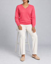 Seated view showing the Hot Pink knit drape of Soft Angle V-Neck Sweater in Hot Pink.