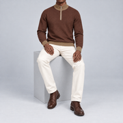 Seated studio view showing Soil knit drape and contrasting Peanut edges of Open Pace Quarter-Zip in Soil with Peanut Trim.