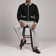 Seated studio view showing knit drape and grey-trimmed patch pockets of Afterlight Knit Bomber in Black with Grey Trim.