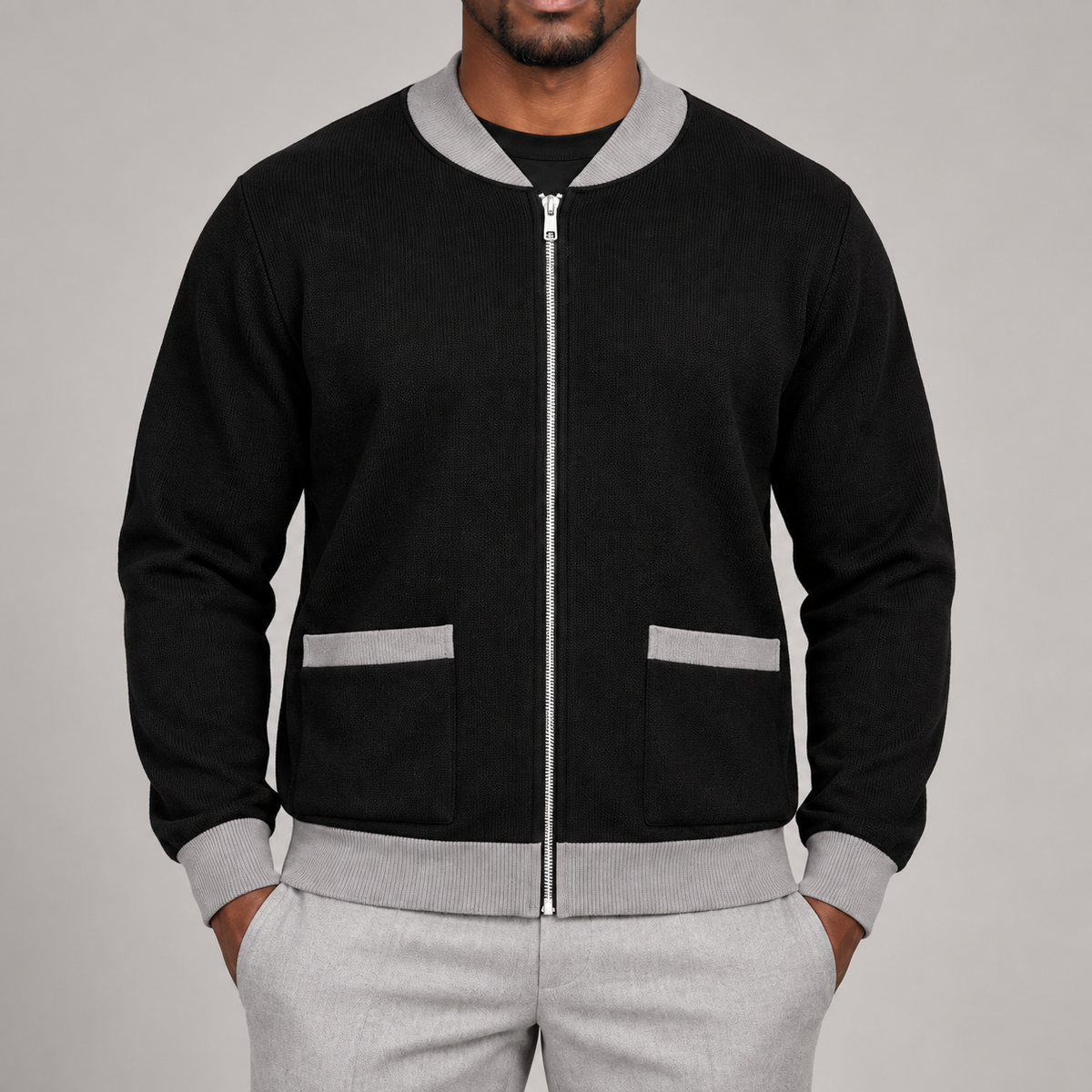 Close-up studio view showing grey collar, silver zipper and patch pockets of Afterlight Knit Bomber in Black with Grey Trim.