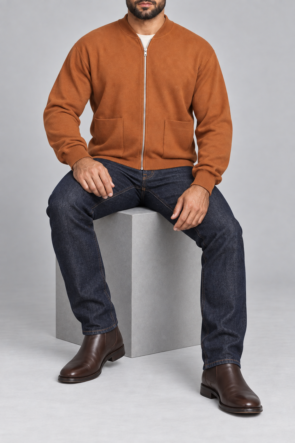 Seated studio view showing knit drape and front pockets of Afterlight Knit Bomber in Rust.