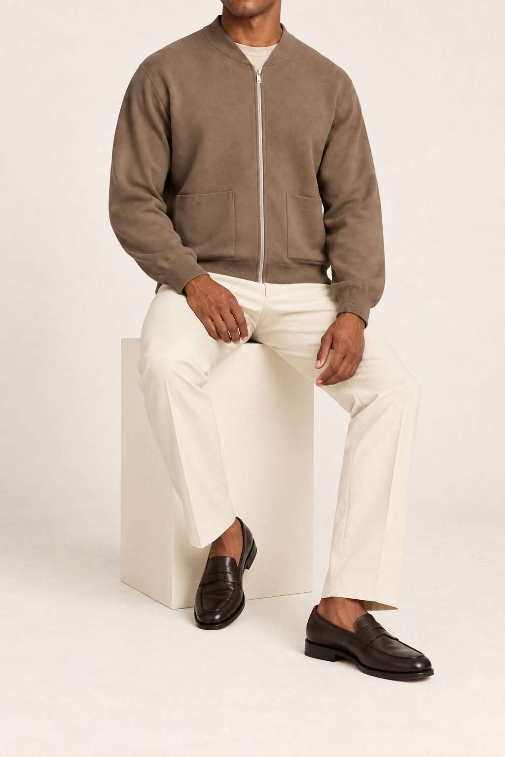 Seated studio view showing knit drape and front pockets of Afterlight Knit Bomber in Peanut.