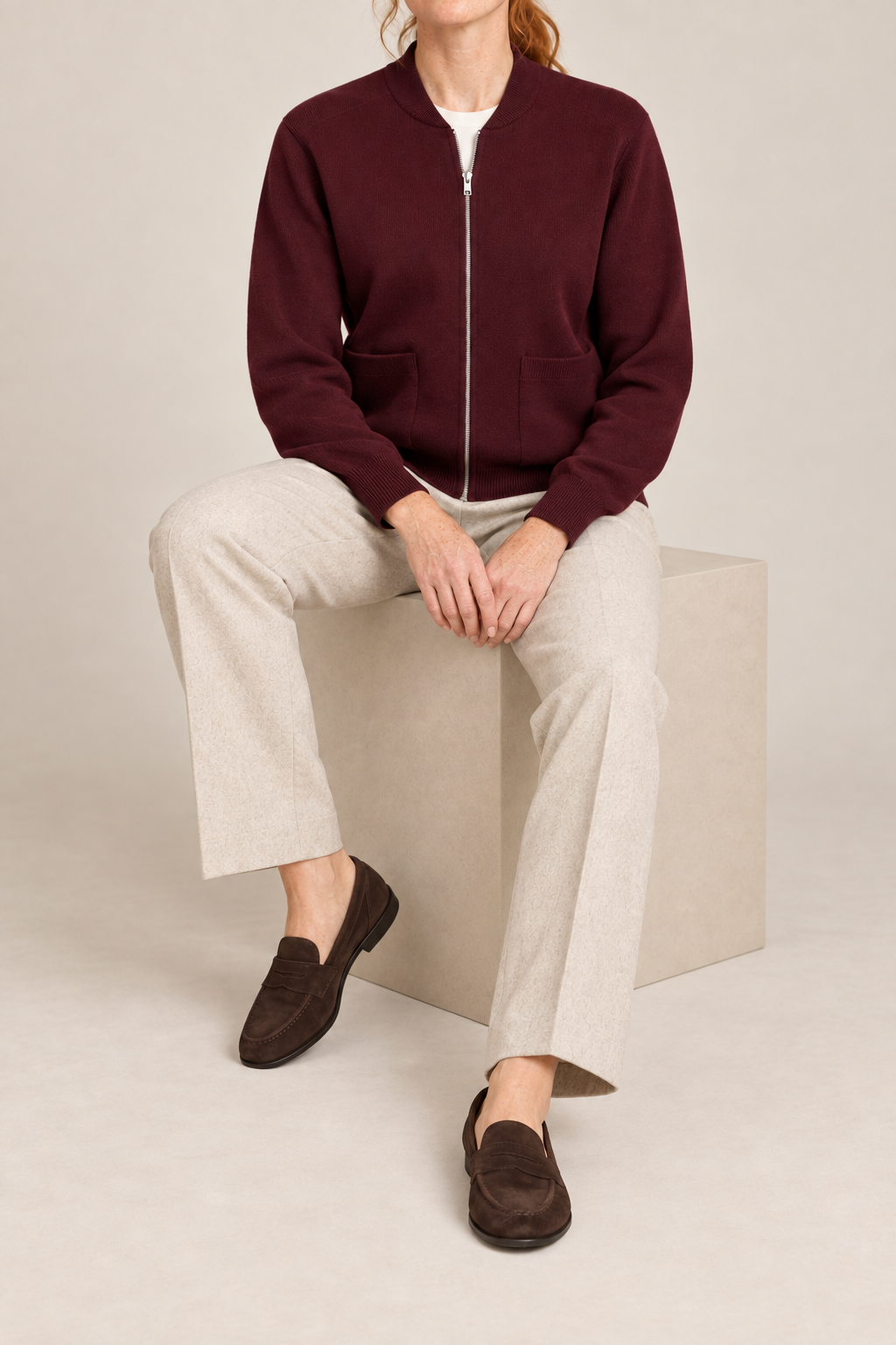 Seated studio view showing knit drape and front pockets of Soft Afterlight Knit Bomber in Burgundy.