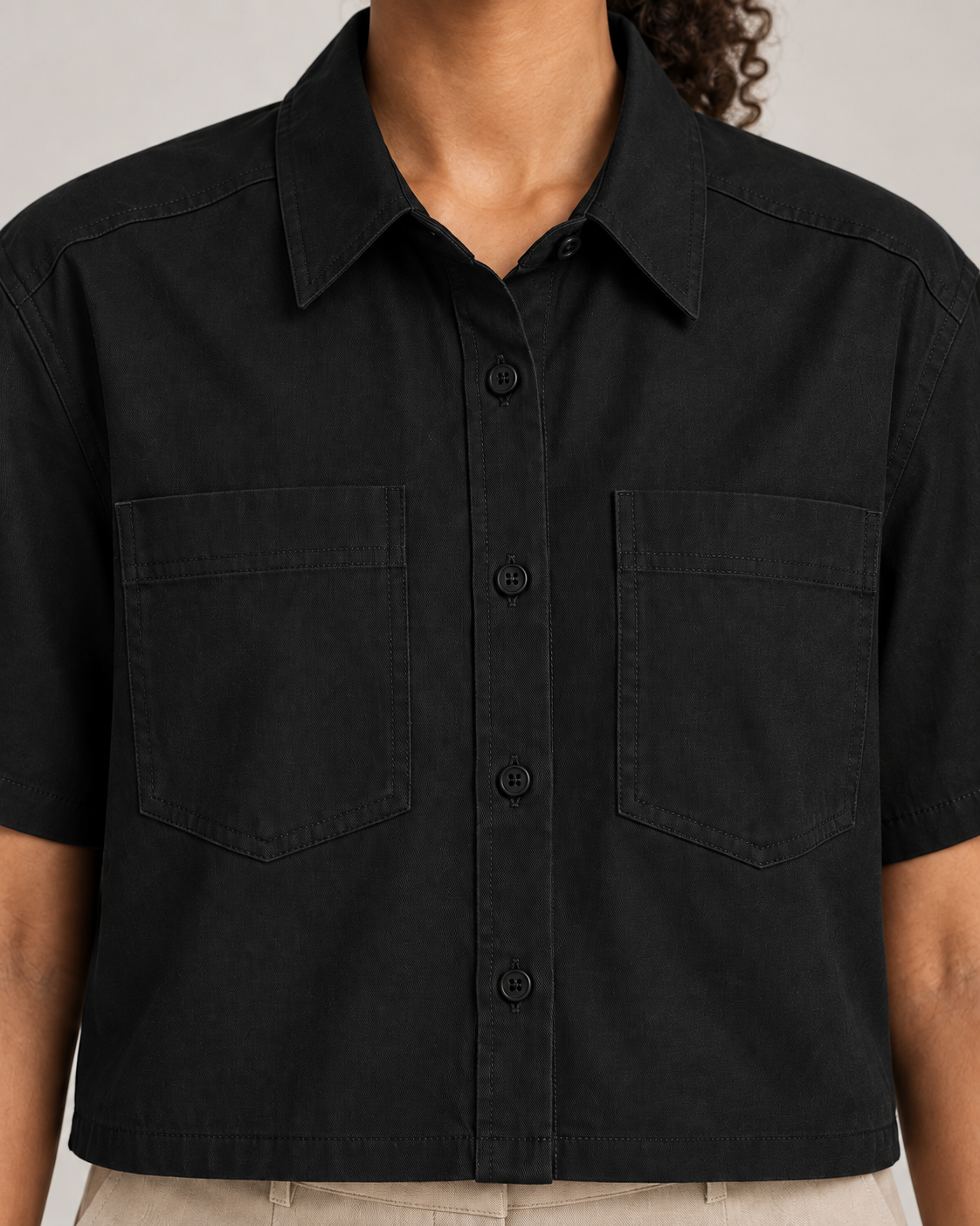 Detail of Quiet Line Crop Shirt in Black, showing collar stitching, black buttons and woven texture.