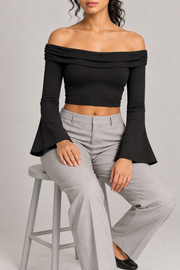 Quiet Fold Bell Sleeve Top in Black. Seated view showing the close fit and flared sleeve drape.
