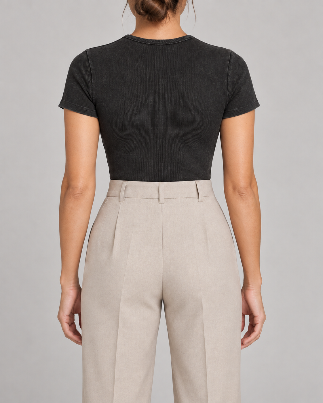 Rear studio view of Soft Trace Bodysuit in Washed Black, showing the plain high neckline and fitted back above beige trousers.