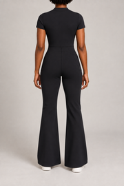 Contour Flare Zip Jumpsuit in Black. Rear studio view showing the back waist seam, curved shaping and plain finish.