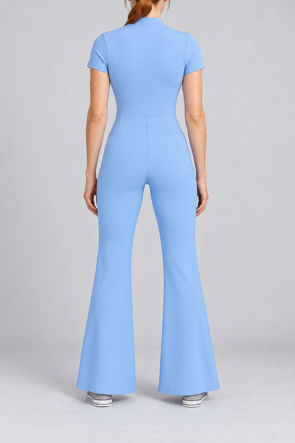 Contour Flare Zip Jumpsuit in Blue. Rear studio view showing the back waist seam and curved shaping above the flared legs.